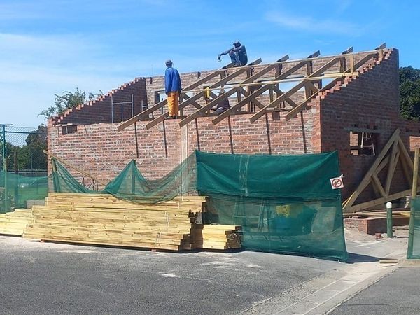 Crew erecting prefabricated timber roof trusses on a brick building