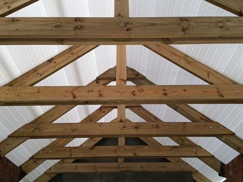 Pre-assembled timber roof trusses against white ceiling panels