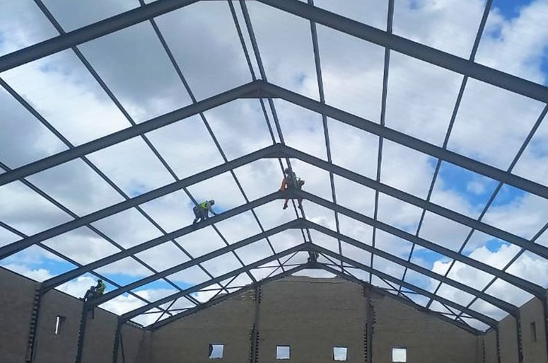 Roof trusses and sheeting being installed on a commercial warehouse by Rome Roofing