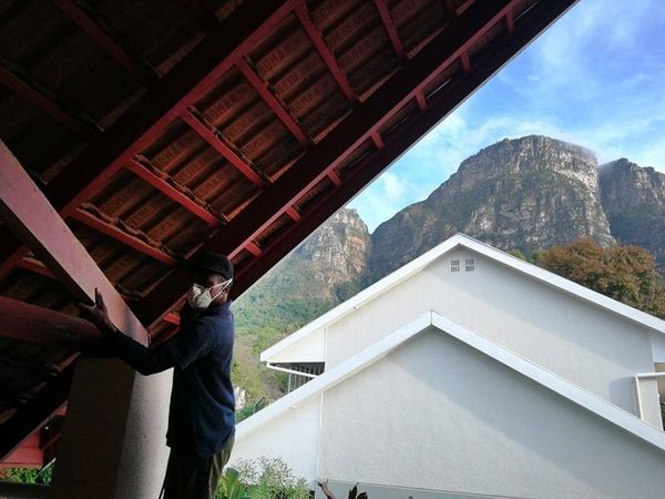 Worker inspecting exposed roof beams with a mountain backdrop