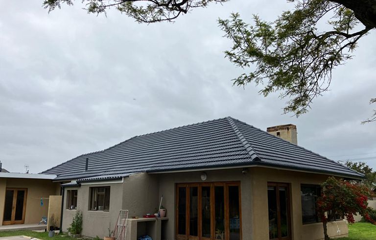 Residential home with a dark tiled roof cared for by Rome Roofing