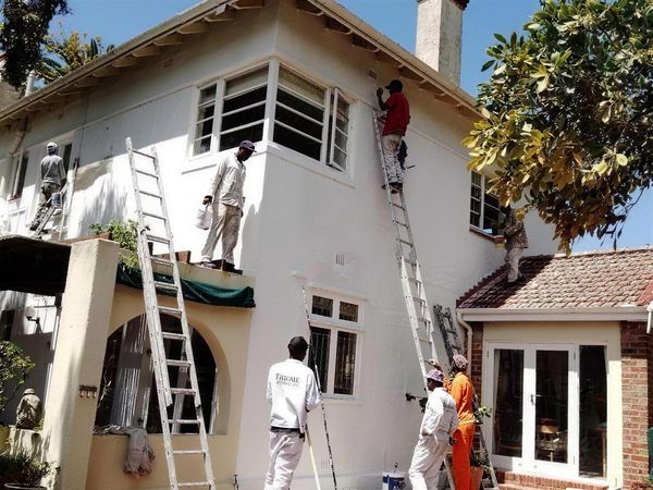 Painting team on ladders working on a home exterior